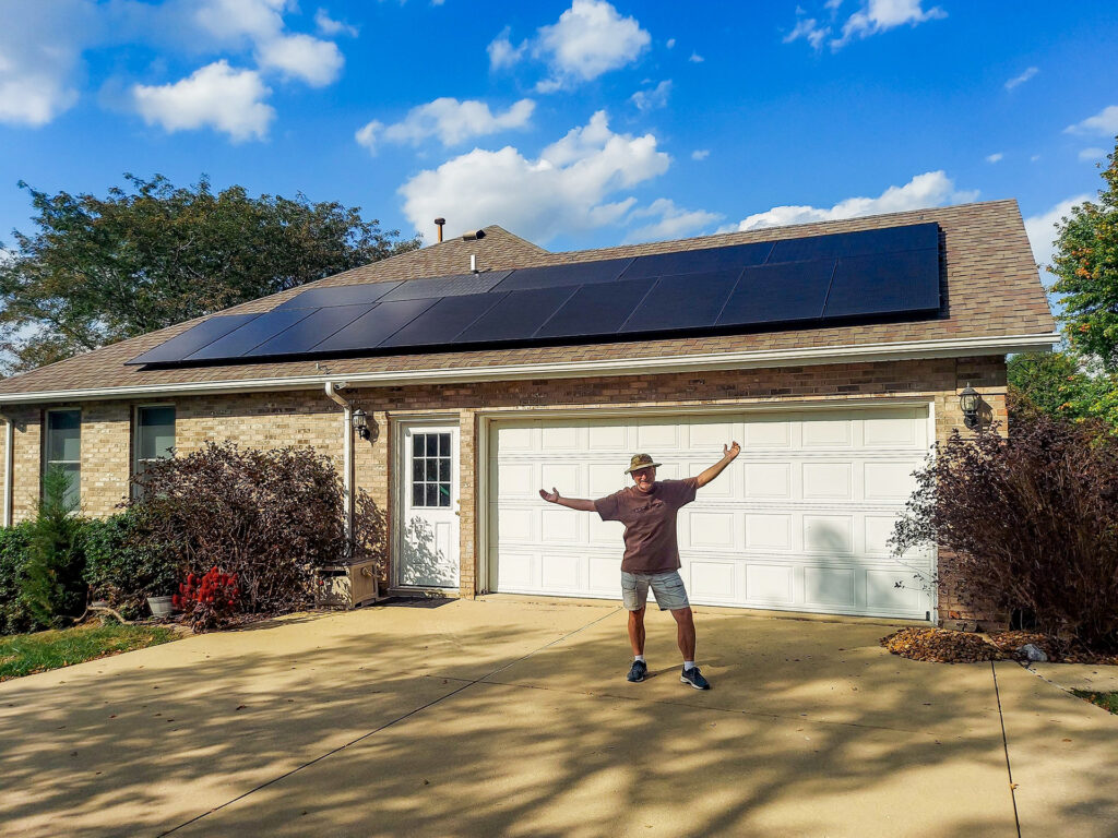 Metro East Illinois Homeowner standing happily in front of his rooftop solar installation from StraightUp Solar on a clear sunny day