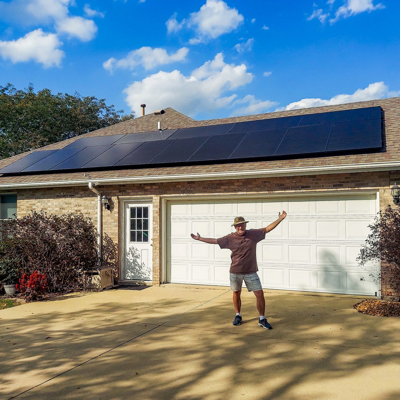 Metro East Illinois Homeowner standing happily in front of his rooftop solar installation from StraightUp Solar on a clear sunny day