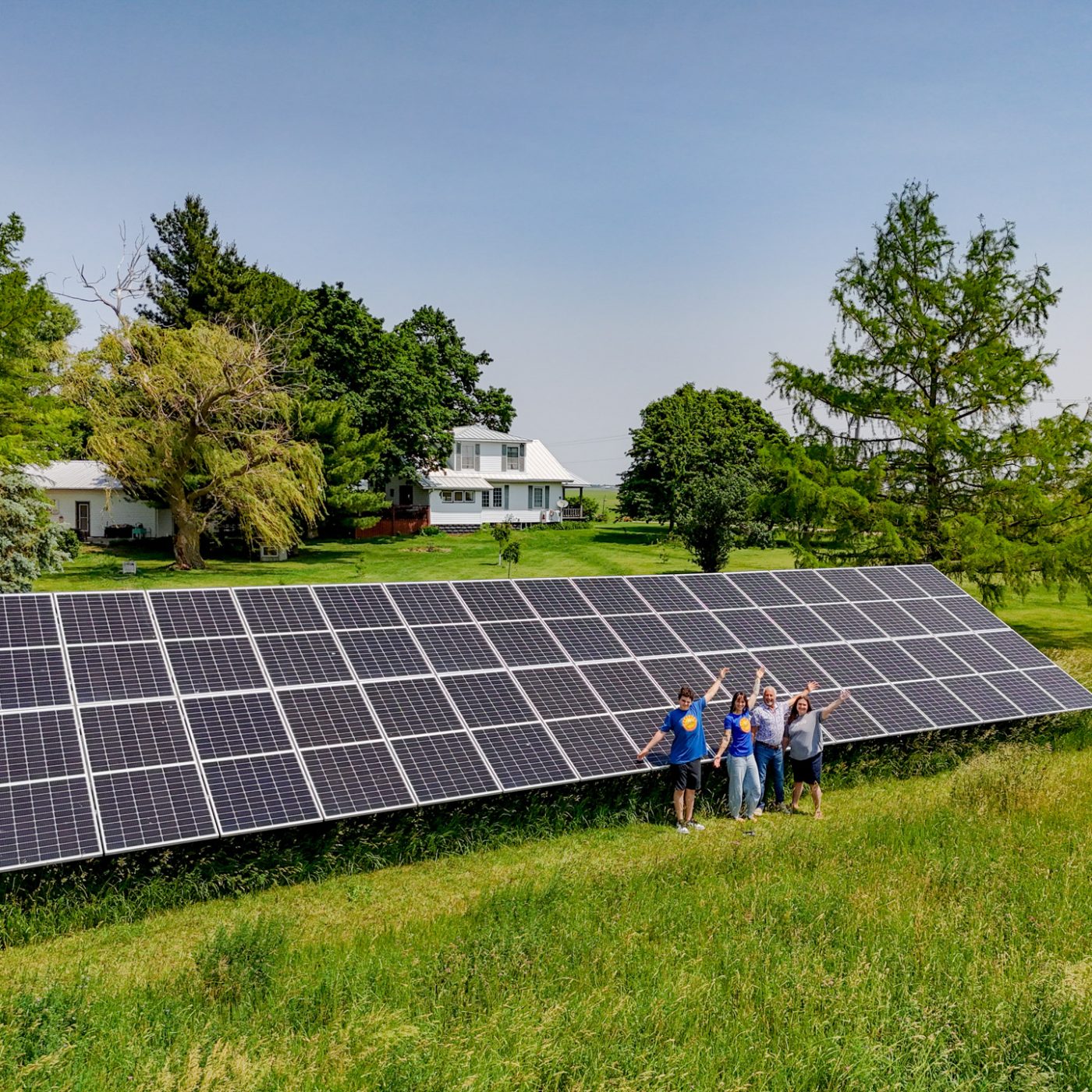 Rural Residential Ground-Mounted Solar Array in Front of White House with Trees and Smiling Family in Illinois | Installed by StraightUp Solar